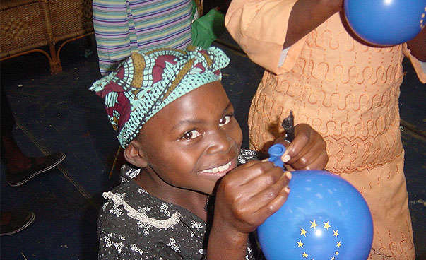 An African girl is inflating a balloon.