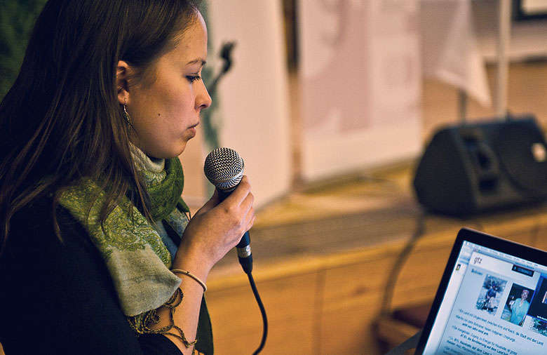 Das Bild zeigt eine Junge Frau auf dem Podium während einer Laptop-Präsentation zum Thema Globales Lernen