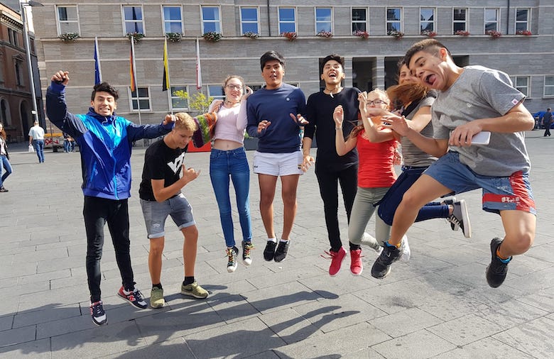 Eine Gruppe von Jugendlichen springt gleichzeitig für ein Foto in die Luft.