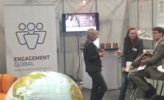 Drei Personen im Gespräch auf dem Messestand von ENGAGEMENT GLOBAL auf der didacta Messe 2012.