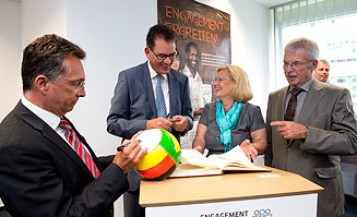 Minister Müller trägt sich ins Gästebuch ein, Staatssekretär Kitschelt signiert den fairen Fußball.