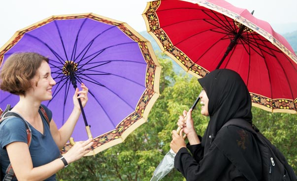 Zwei Frauen mit bunten Schirmen unterhalten sich.