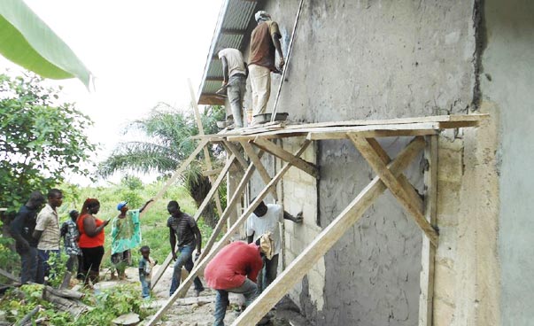 Afrikaner verputzen die Aussenwände eines Hauses.
