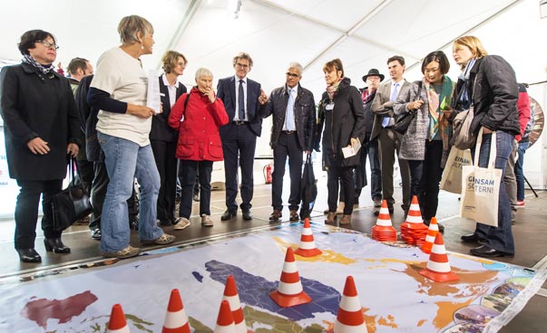 Das Bild zeigt eine Gruppe von Menschen die über einer Weltkarte am Boden stehen, das Weltverteilungsspiel.