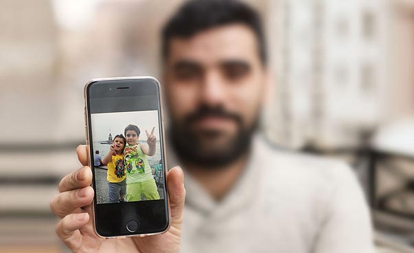 Ein Mann zeigt ein Foto seiner zwei Kinder auf dem Smartphone. Foto: David Campesino