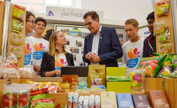 Der Bundesminister Dr. Gerd Müller lässt sich von Schülern einen fairen Kiosk zeigen.