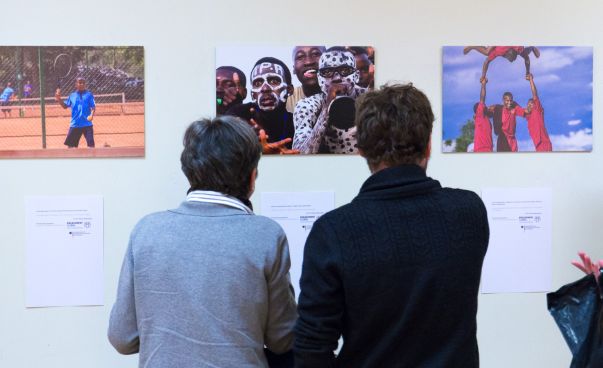 Zwei Menschen sind von hinten zu sehen, wie sich Bilder einer Ausstellung ansehen.