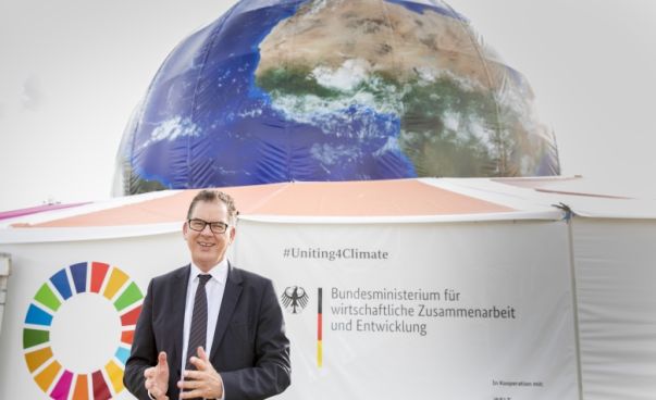 Bundesentwicklungsminister Gerd Müller steht vor einem großen Nachbau der Erde.