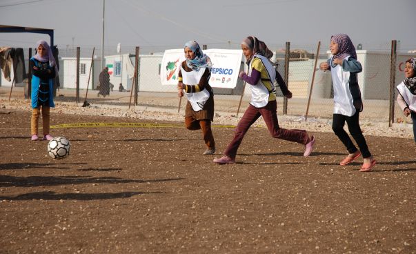 Junge Mädchen mit Kopftüchern spielen in einem Flüchtlingscamp Fußball.