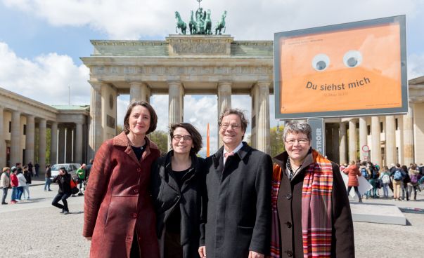 Vier Menschen posieren vor dem Brandenburger Tor.