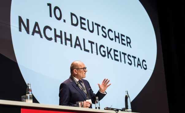 Ein Mann spricht an einem Podium beim 10. Deutschen Nachhaltigkeitstag.