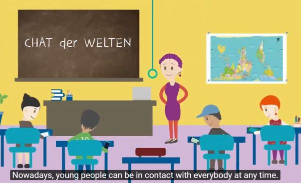Screenshot aus dem Chat der Welten Video: Eine Frau steht an einer Tafel vor einer Schulklasse. Foto: Engagement Global