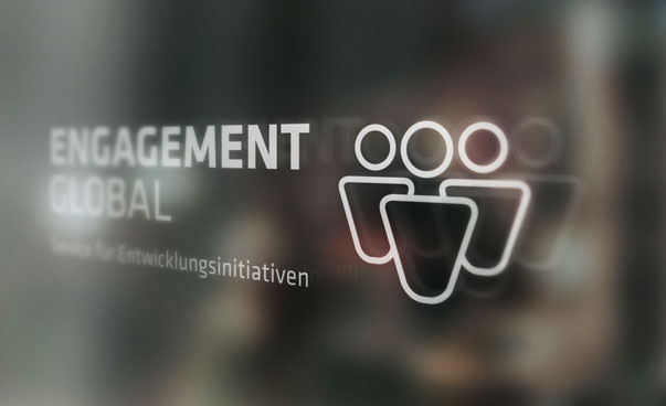 Das Logo von Engagement Global zeigt den Namen der Organisation in grauer und blauer Schrift. Zudem sind auf der rechten Seite drei Kegel zu erkennen.
