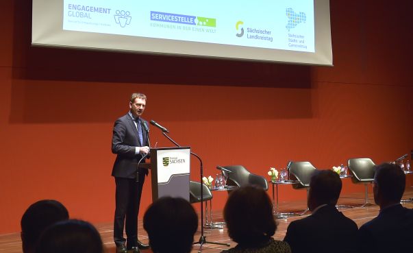 Ministerpräsident Michael Kretschmer steht auf der Bühne am Rednerpult vor einem Publikum. Foto: Engagement Global/Matthias Rietschel
