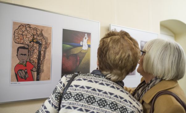 Zwei ältere Frauen betrachten Karikaturen zum Thema Flucht in einer Ausstellung. Foto: Thomas Keydel