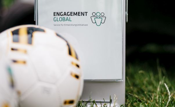 Ein weißer Fußball liegt vor einem Schild, auf dem Engagement Global steht. Foto: René Frampe