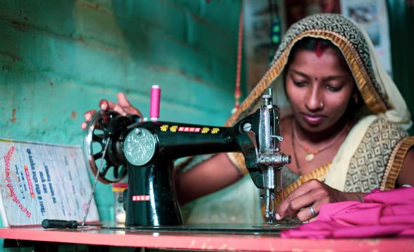Eine Frau in traditioneller Kleidung arbeitet an einer Nähmaschine.