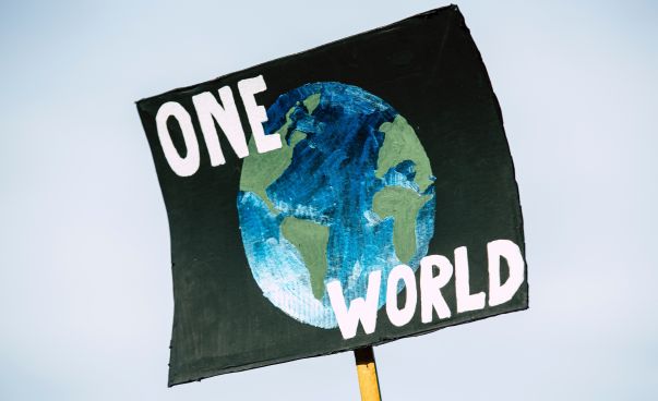 Plakat, auf dem eine Weltkugel zu sehen ist. Text: One World