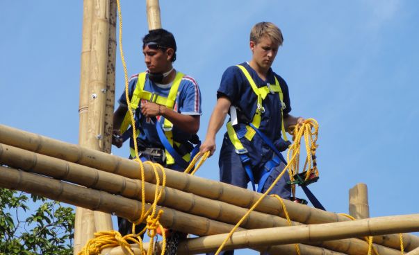 Zwei junge Männer arbeiten auf einem Bambusgerüst.
