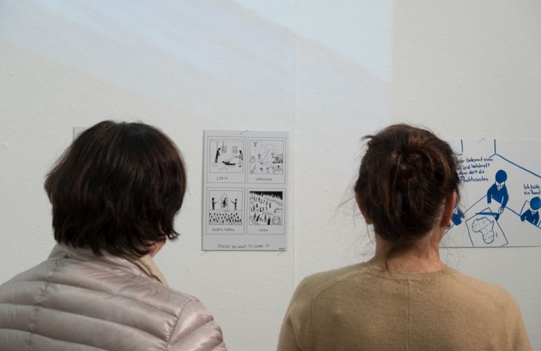 Zwei Frauen betrachten Karikaturen.
