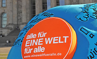 Blaue Weltkugel mit Logo des Schulwettbewerbs vor dem Berliner Reichstag.