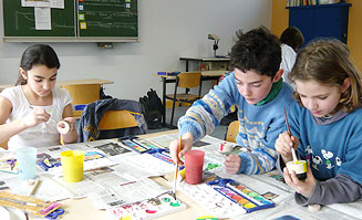 Kinder malen gemeinsam an einem Gruppentisch
