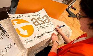 Eine Referentin beschriftet ein Plakat des ASA Programms