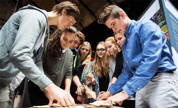 Mehrere Jugendliche beugen sich über ein Spiel auf einem Tisch. Foto: Andreas Henn