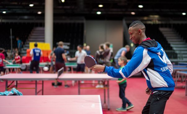 Ein junger Mann steht an einer Tischtennisplatte und schlägt den Ball. Foto: René Frampe