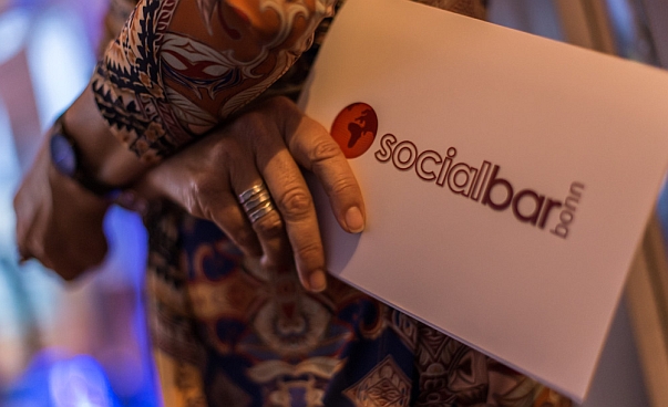 Eine Hand hält eine Karte mit dem Aufdruck Socialbar.