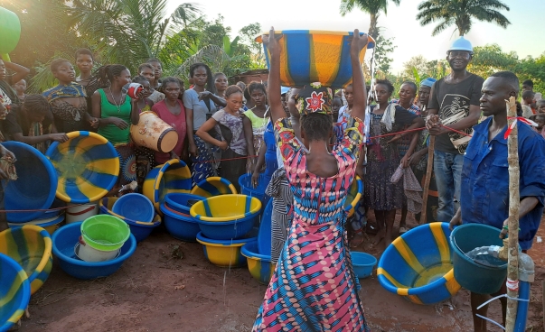 Eine Gruppe von Menschen hält Schalen mit Wasser in der Hand.