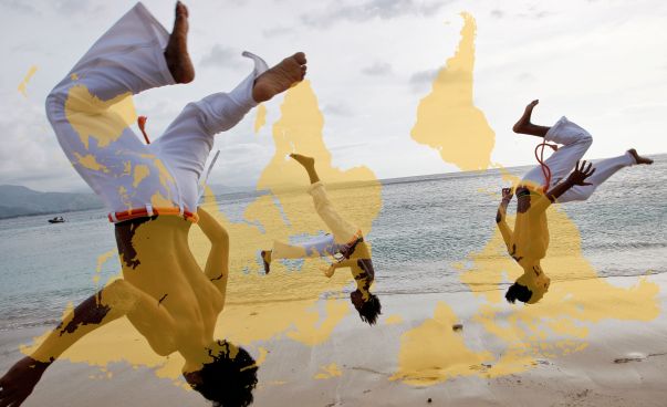 Drei Menschen machen Capoeira-Bewegungen.