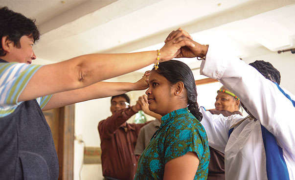 Eine indische Frau steht unter einem Dach, das zwei Menschen mit ihren Armen bilden.